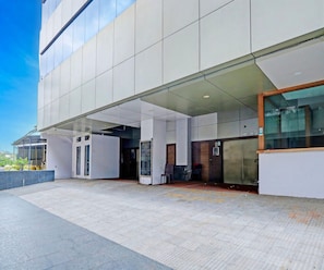En modern byggnad med en överbyggd entré, en sittplats och en klar himmel.
