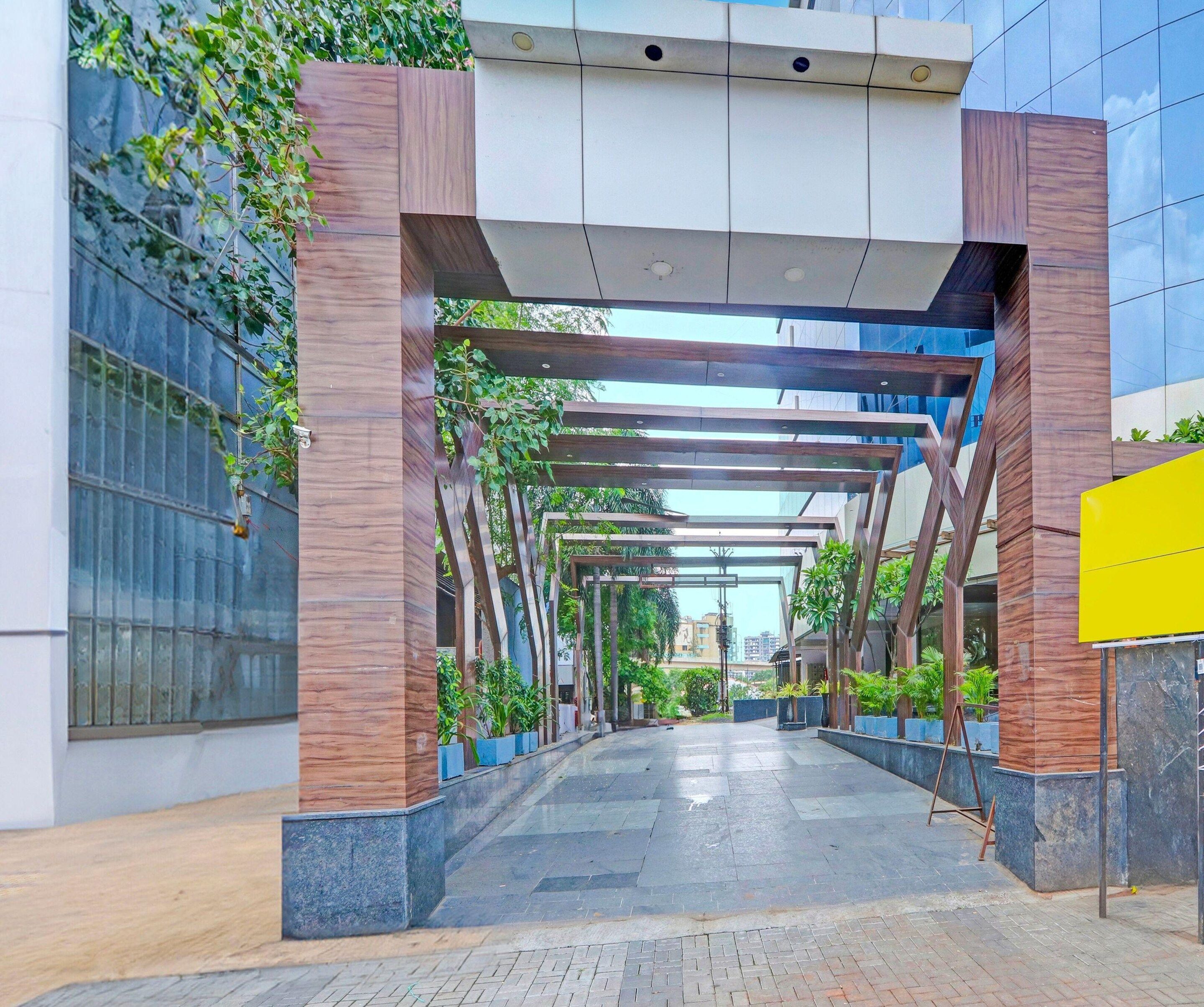 A covered walkway with a modern architectural design, featuring a combination of wooden and metal elements, and a paved pathway.
