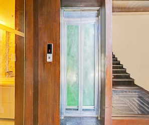 Una puerta de madera con un panel de vidrio y un panel de control digital para el ascensor.