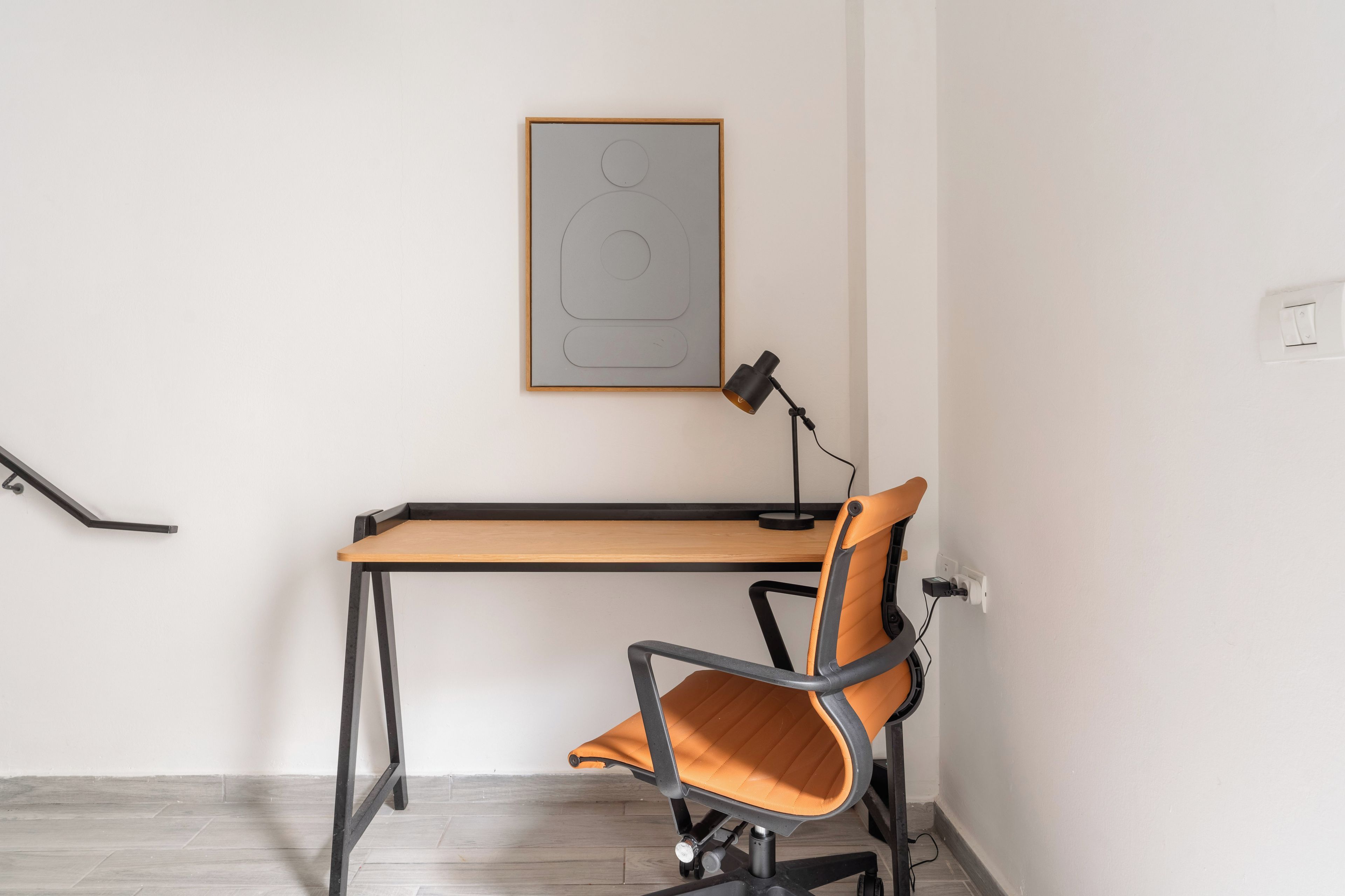Un espace de travail comprenant un bureau, une chaise et une œuvre d’art abstraite encadrée accrochée au mur.