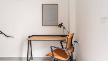 Un espace de travail comprenant un bureau, une chaise et une œuvre d’art abstraite encadrée accrochée au mur.
