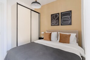 A hotel room with a bed, a nightstand, a lamp, and two abstract wall art pieces.