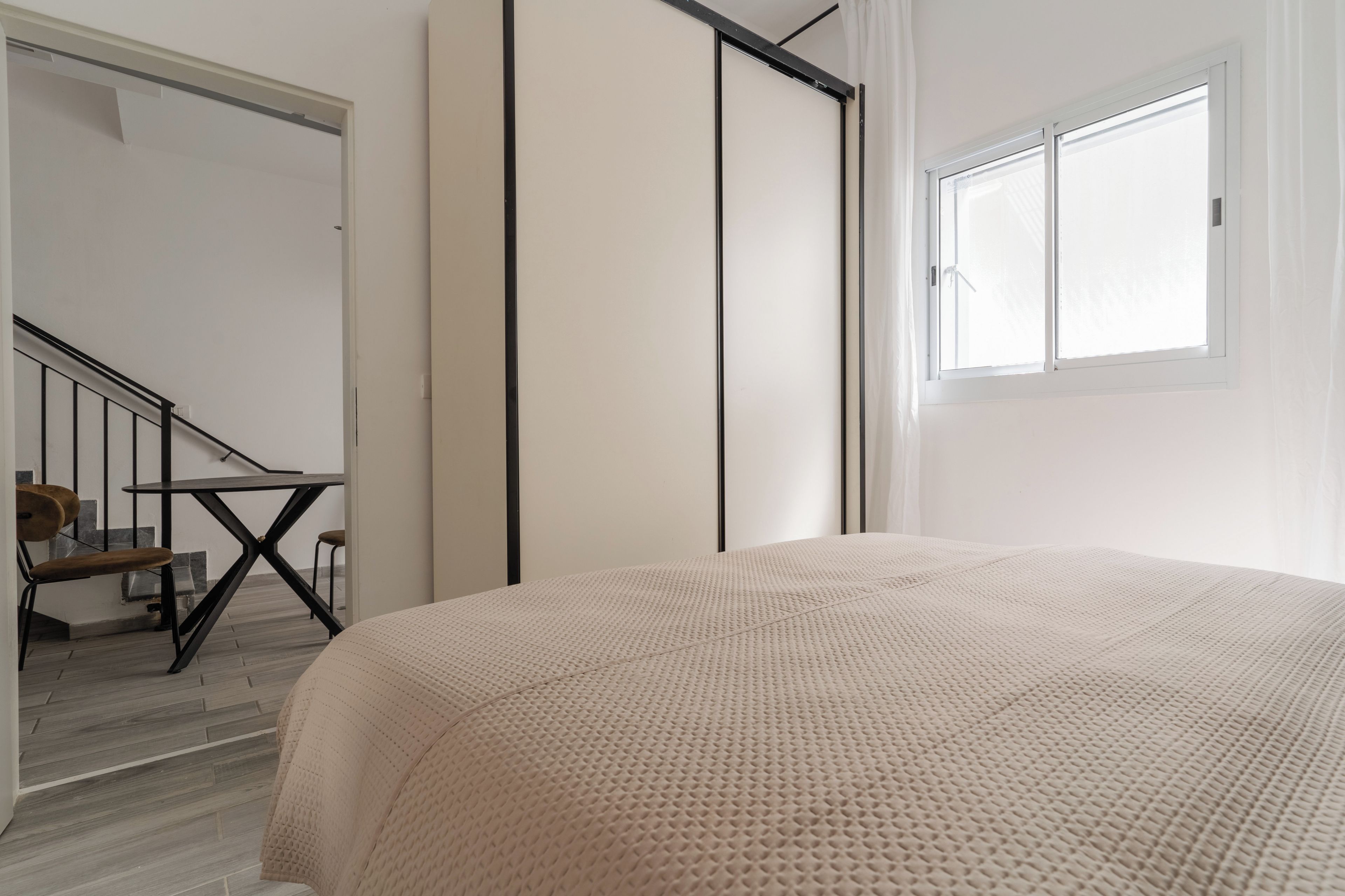 Une chambre à coucher avec un lit, une fenêtre, un escalier et une porte.