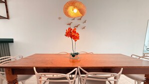 Un comedor con mesa de madera, sillas blancas y una lámpara colgante.