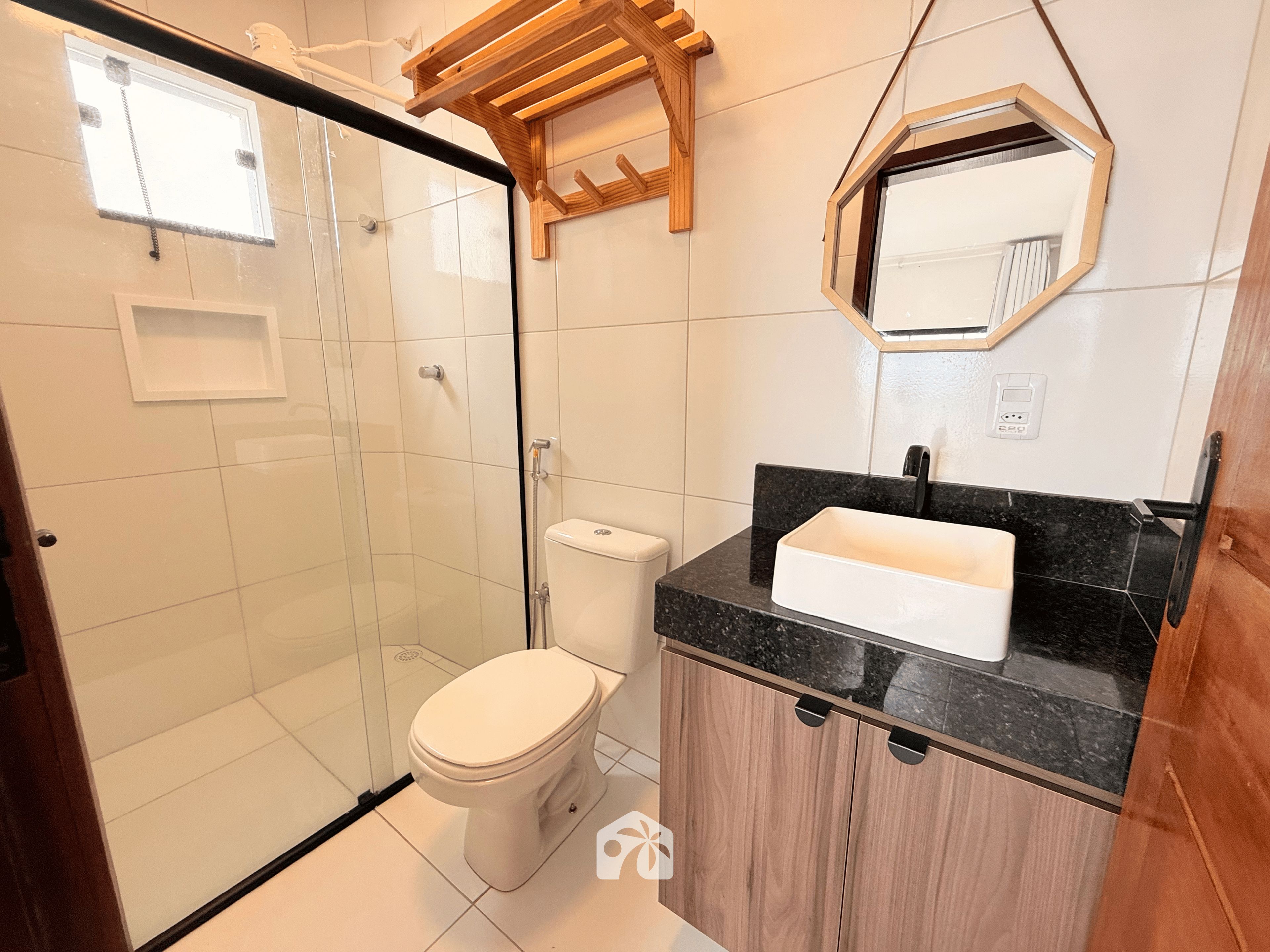 Un baño con ducha, inodoro, lavabo y un estante de madera.