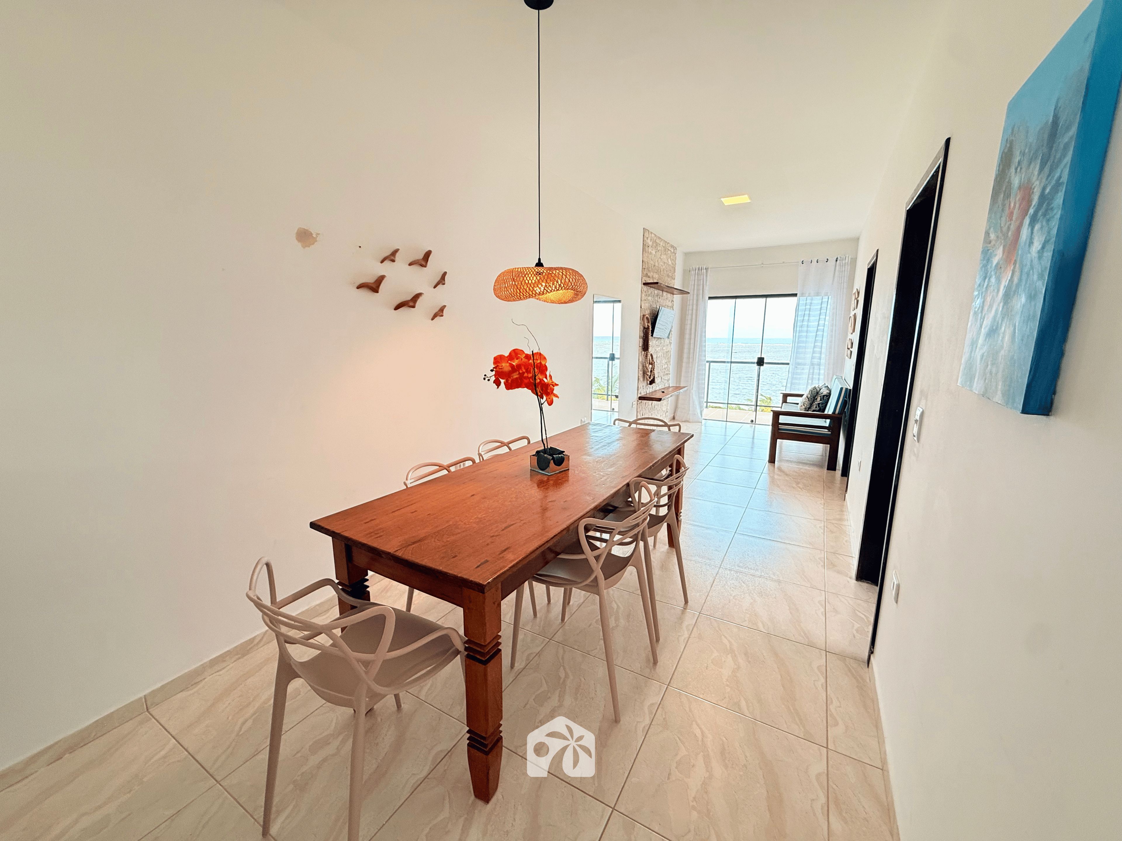 A dining area with a wooden table, chairs, and a hanging light fixture.