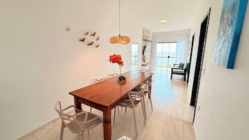 A dining area with a wooden table, chairs, and a hanging light fixture.