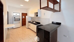 Una cocina moderna con encimera negra, armarios blancos y estructura de techo de madera.