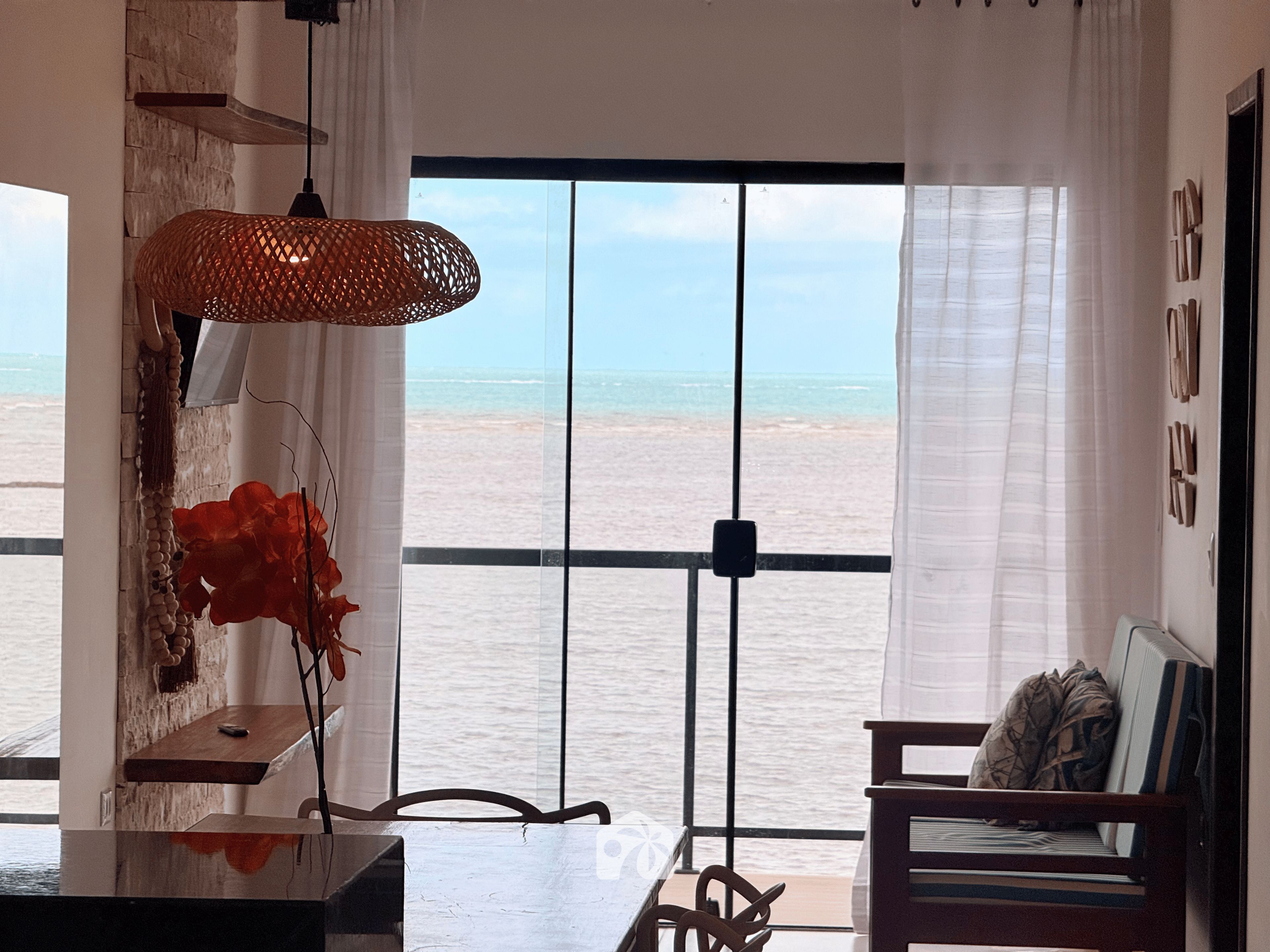 Una habitación con vista al mar, una mesa de madera, una silla y una lámpara colgante.