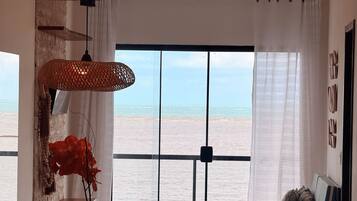 Una habitación con vista al mar, una mesa de madera, una silla y una lámpara colgante.