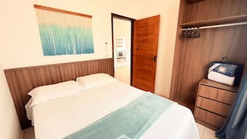 A bedroom with a bed, a wooden wardrobe, and a wall-mounted artwork.