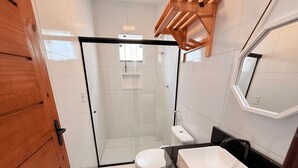 Un baño moderno con ducha de vidrio, inodoro blanco y un lavamanos grande.