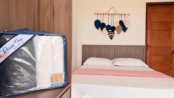 Quarto com cama, guarda-roupa de madeira e um objeto decorativo na parede.