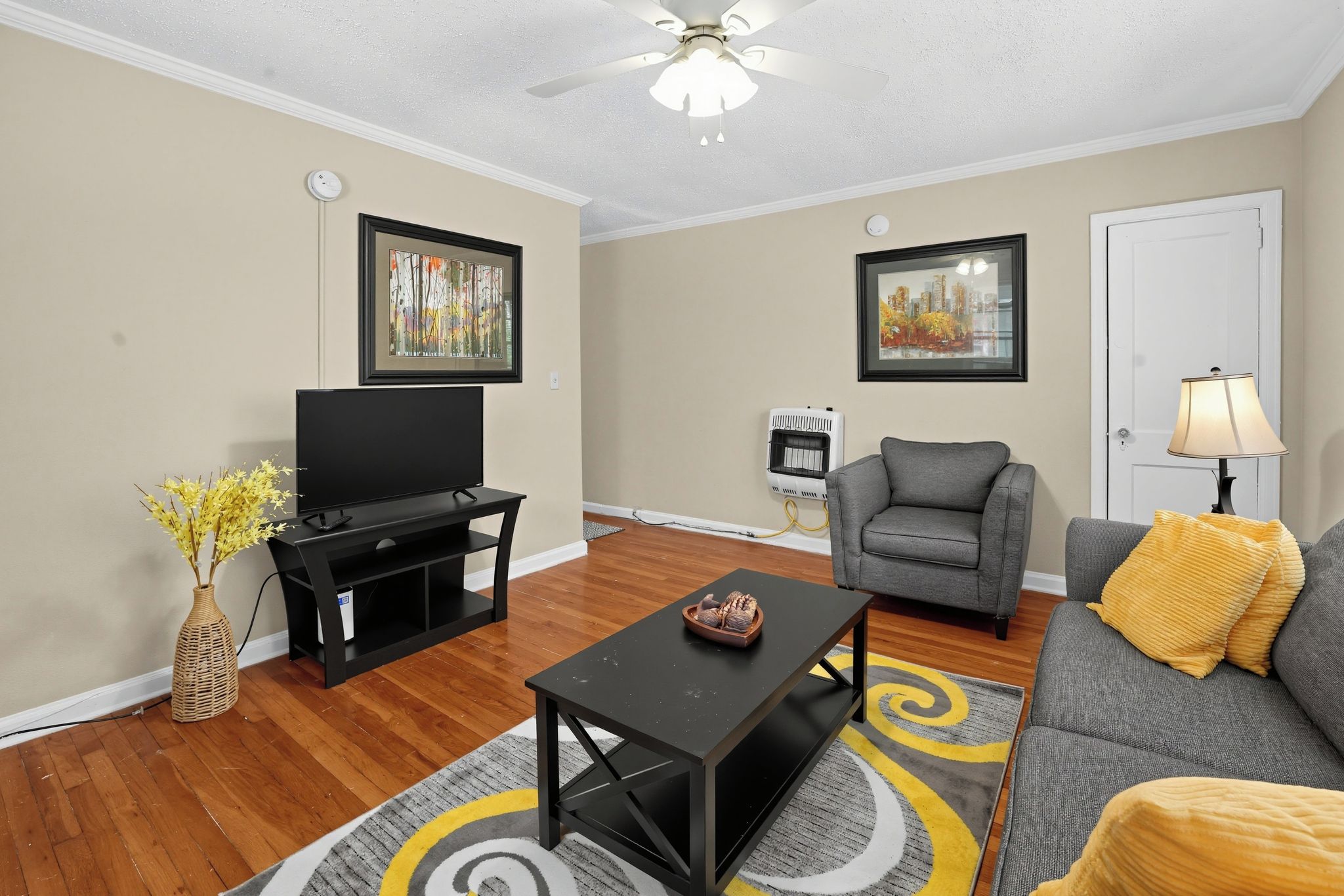 A living room with a flat-screen TV, a gray sofa, a coffee table, and a floor lamp.