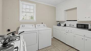A laundry room with a washing machine, dryer, stove, and microwave.