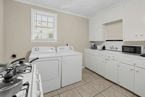 A laundry room with a washing machine, dryer, stove, and microwave.