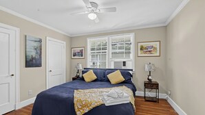 Una camera da letto con un letto, due comodini, una ventola a soffitto e opere d'arte alle pareti.