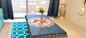 Ein Zimmer mit einem gemusterten Tischläufer, einer Blumenvase, einem gemusterten Teppich und einer dekorativen Vase auf einem Beistelltisch.