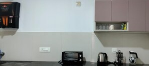 Una cuina equipada amb cafetera, torradora, bullidor i utensilis.