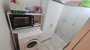 Eine kompakte Küchenzeile mit Mikrowelle, kleinem Backofen und Waschmaschine.