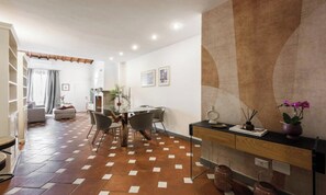 A dining area with a table and chairs, a kitchen in the background, and a decorative wall. - BEAUTIFUL FLORENCE APARTMENT WITH PRIVATE TERRACE NEAR THE DUOMO (Firenze)