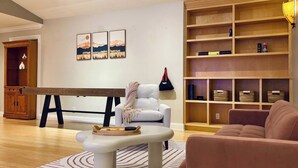 Een woonkamer met een biljarttafel, een bank, een salontafel en een boekenkast.