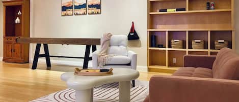 A living room with a billiards table, a sofa, a coffee table, and a bookshelf.
