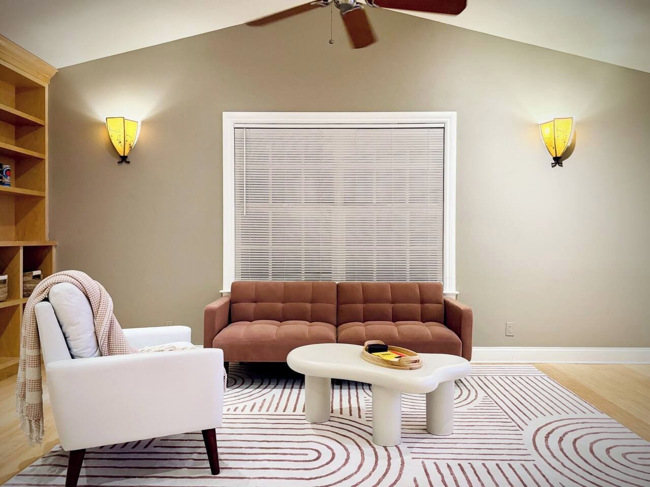 Sala de estar com sofá, poltrona, mesa de centro e duas luminárias de parede.