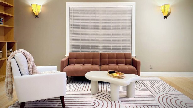 Ein Wohnzimmer mit Sofa, Sessel, Couchtisch und zwei Wandleuchten.