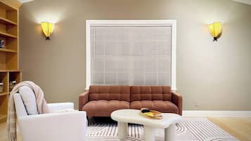 Sala de estar com sofá, poltrona, mesa de centro e duas luminárias de parede.