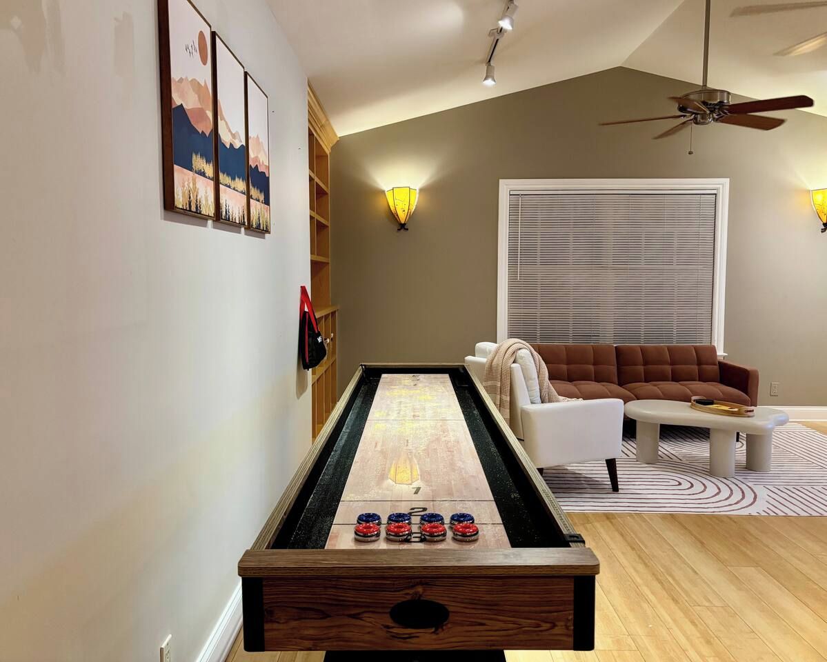 Une pièce comprenant une table de jeu de palet, un canapé et un ventilateur de plafond.