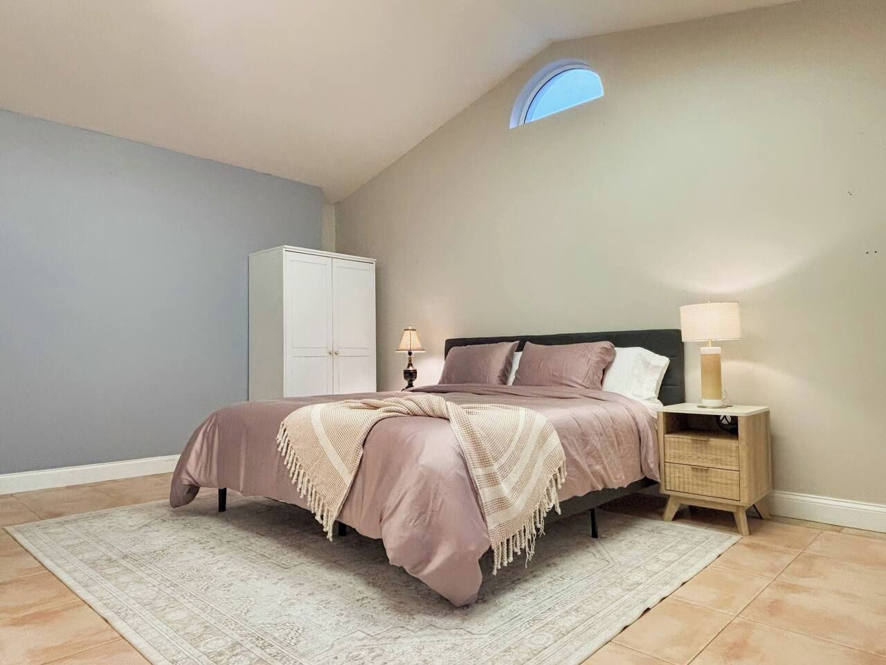 Ein Schlafzimmer mit Bett, Nachttisch, Lampe und einem Kleiderschrank.