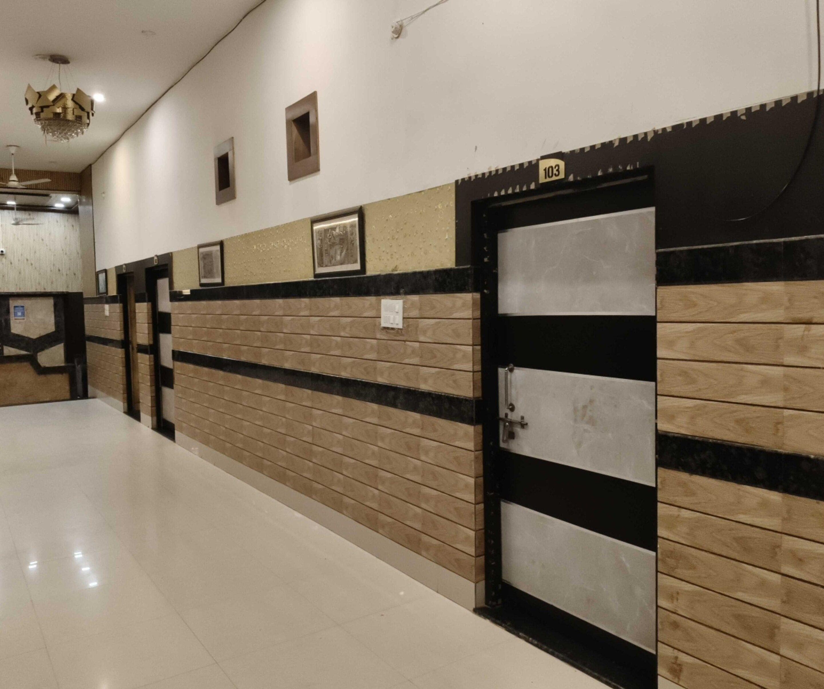 Un pasillo con piso de baldosas, una pared con diseño decorativo y una puerta con un letrero de número.