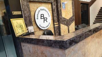 A reception desk with a marble top, a framed sign above it, and a chair to the left.