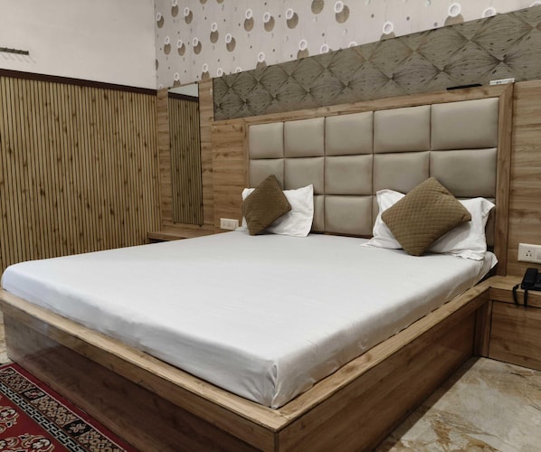A double bed with a wooden frame and headboard, two pillows, and a bedside table with a phone.
