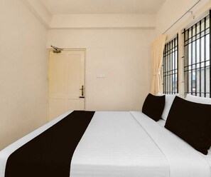 Una habitación con una cama, una puerta y una ventana con barrotes.