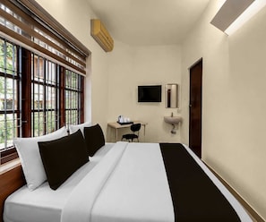 Una camera d'albergo con un letto, una scrivania con una sedia, una televisione, un lavandino e una finestra con persiane.