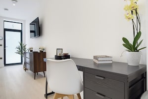 A modern office space with a desk, chair, and potted plants.