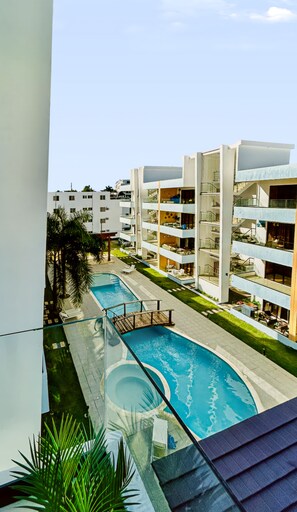 A modern apartment complex with a swimming pool, balconies, and a clear sky. - The Reef · Pool & Home Cinema - Mins to Beach (Bayahíbe)