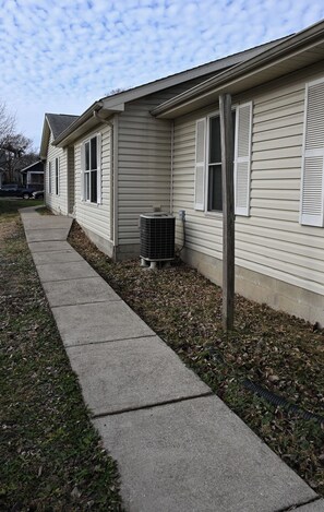 A residential building with a concrete pathway, a window with shutters, and an air conditioning unit. - Cozy Fall Getaway in Broadripple (Indianapolis)