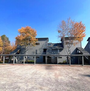 A two-story building with a covered porch and a gravel driveway. - Lovely 2-bedroom condo next to Teton Village/Skii Mountain Resort (Wilson)