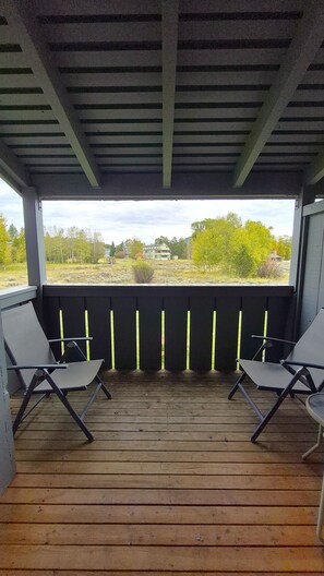 An outdoor deck with two lounge chairs and a view of a building and trees. - Lovely 2-bedroom condo next to Teton Village/Skii Mountain Resort (Wilson)