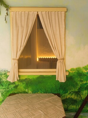 Una habitación con ventana, una cama y vistas a un paisaje verde.