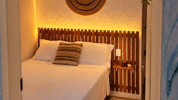 Un dormitorio con cama, cabecera de madera, un adorno en la pared y un cartel sobre la cama.