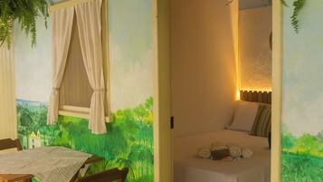 A room with a bed, a table with chairs, and a mural of a landscape.