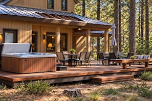 Una terraza de madera con jacuzzi, mobiliario exterior y un porche cubierto.