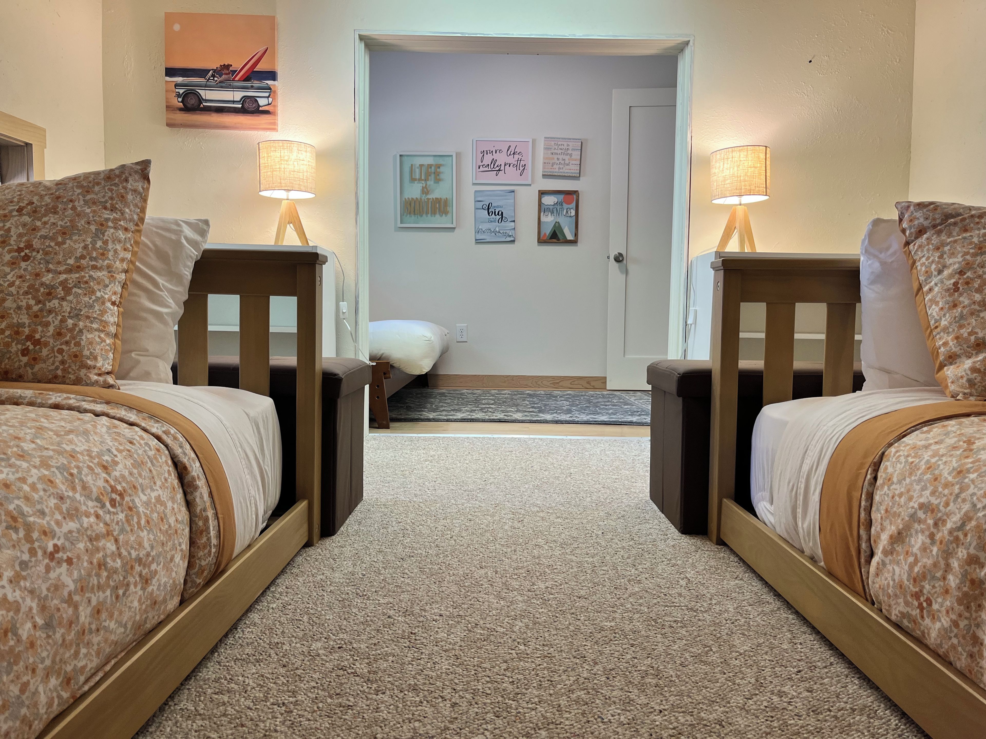 A bedroom with two beds, a door, and a wall with motivational posters.