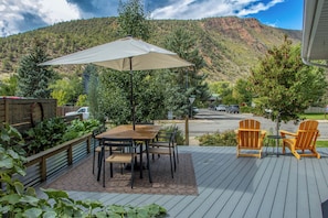 A deck with a table and chairs, a large umbrella, and a view of a mountain. - Garden Getaway Gardens, Canyon View, River Trail (Glenwood Springs)