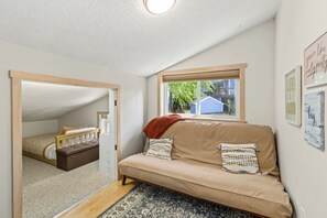 Una habitación acogedora con sofá, ventana con vistas, puerta que conduce a otra habitación y una lámpara en el techo.