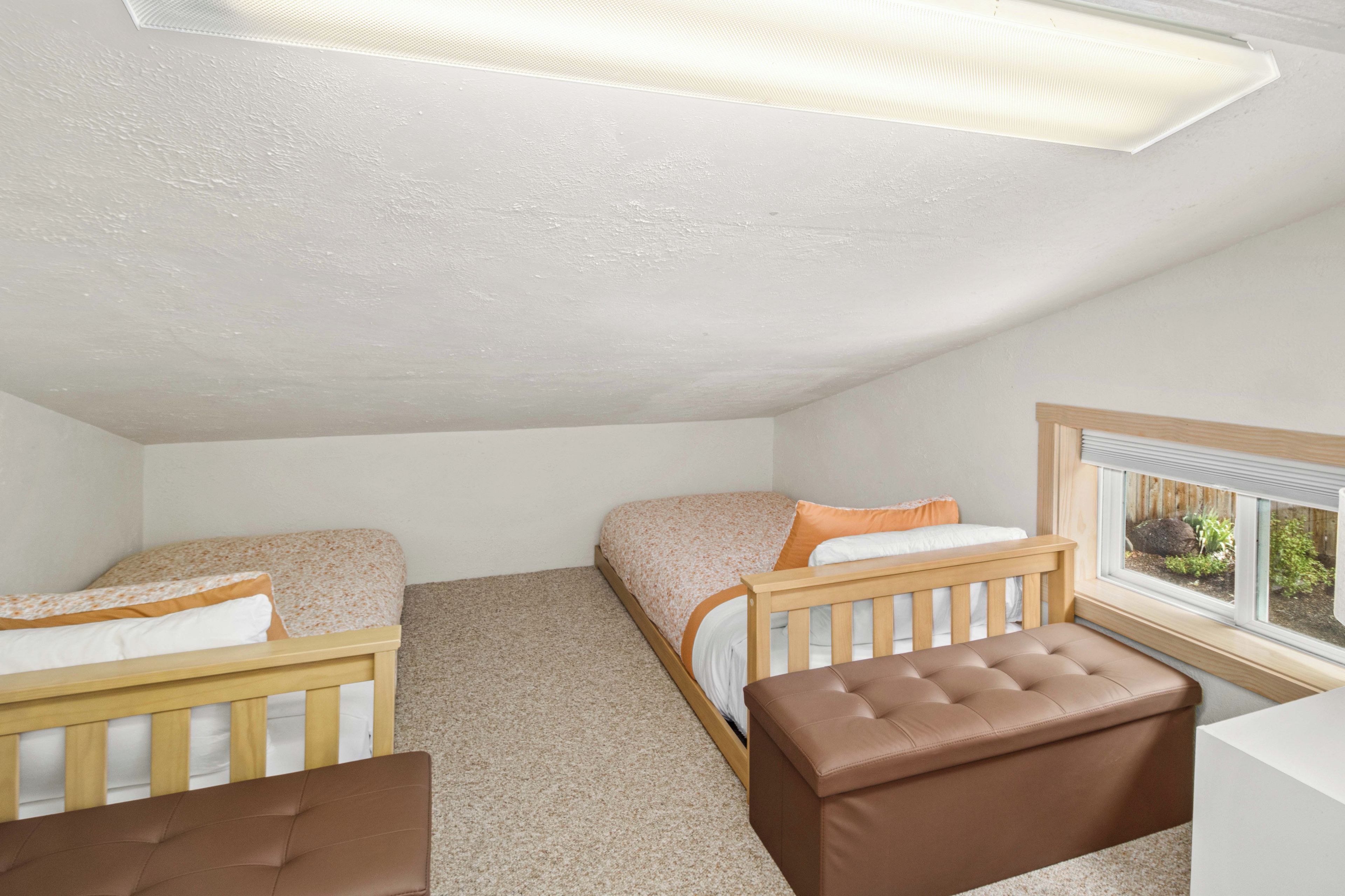 Une chambre avec deux lits simples, un banc en bois, une fenêtre avec vue et un luminaire au plafond.